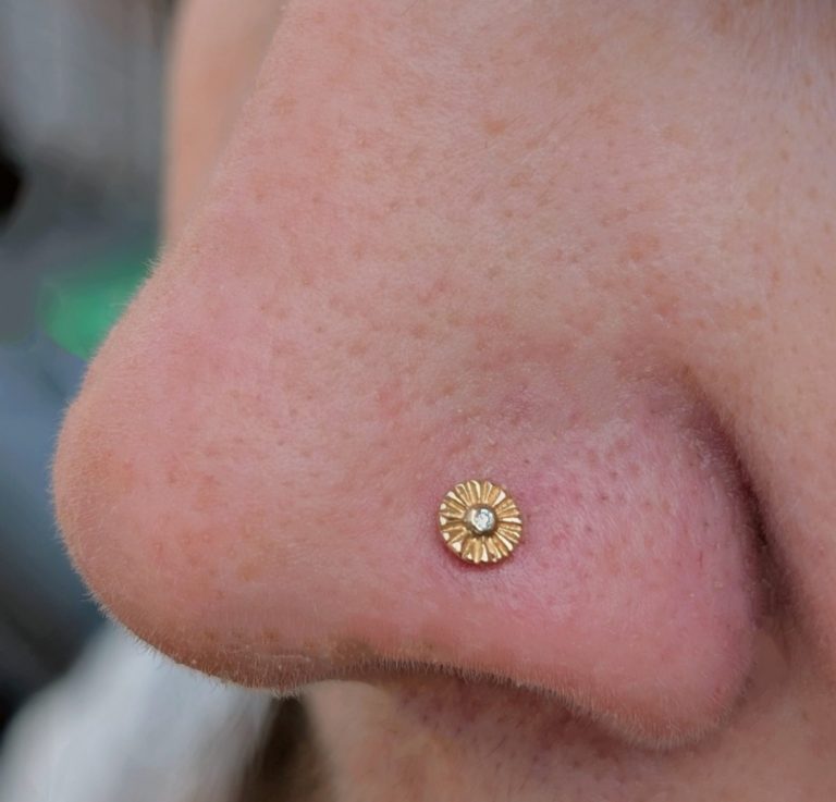 nose piercing featuring a small gold flower stud by local natives.